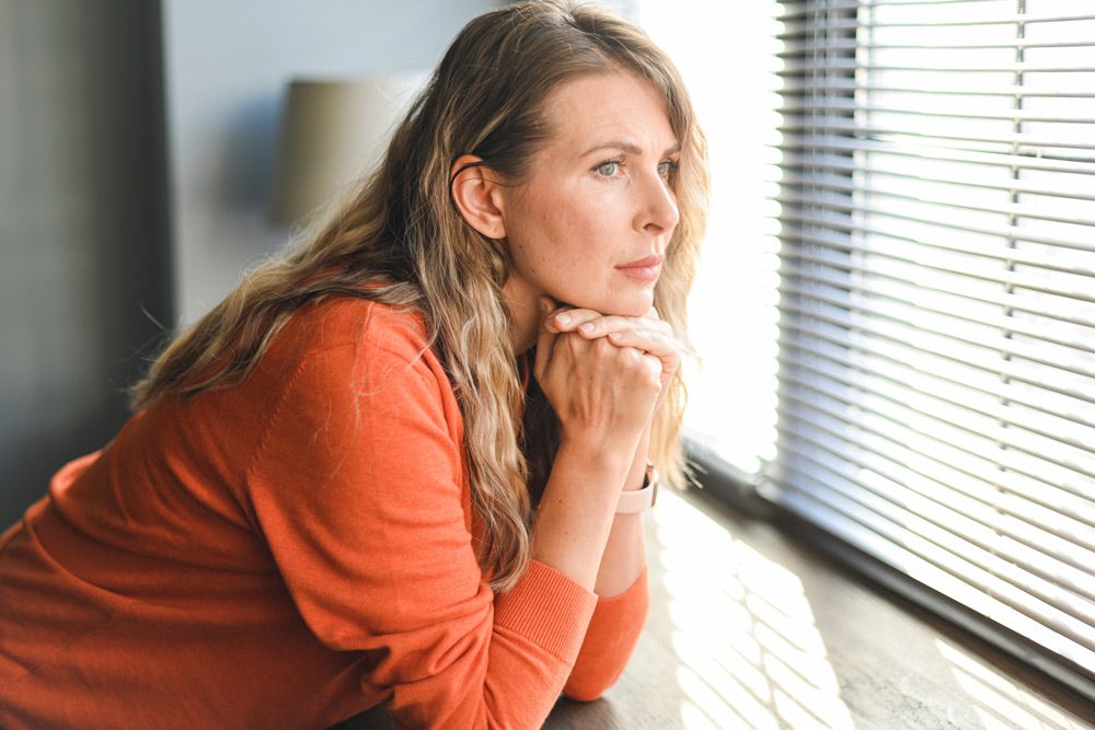 pensive woman looking out a widow