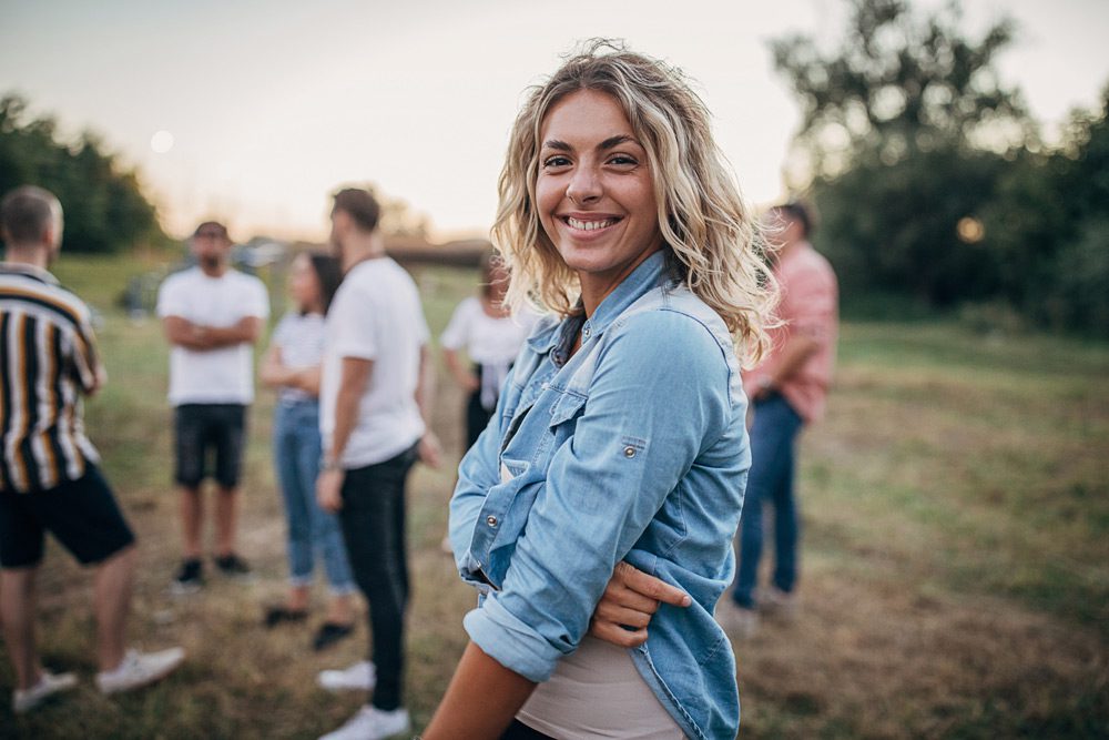 smiling woman outside with a group of friends in the background