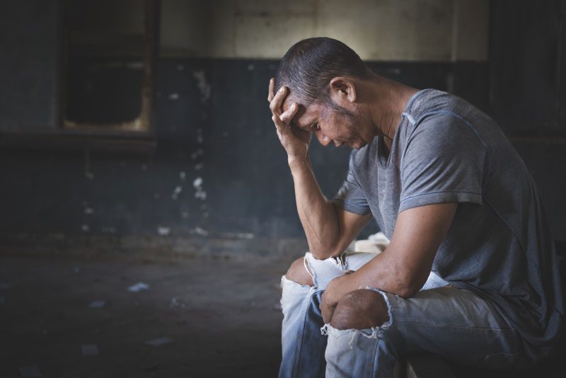 man sitting with his head in his hand, clearly upset and distressed