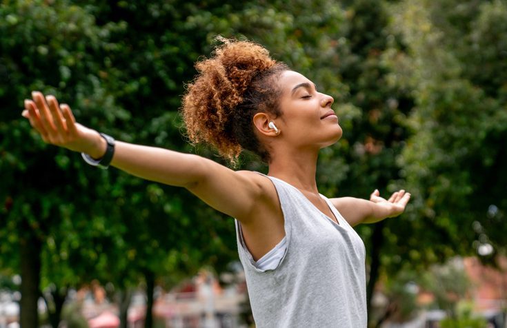 woman standing outside with her arms outstretched in gratitude - mental health