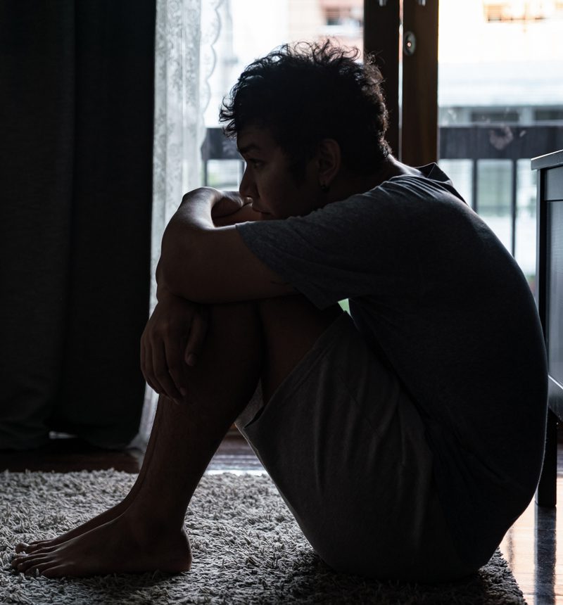 sad man sitting on the floor of his bedroom