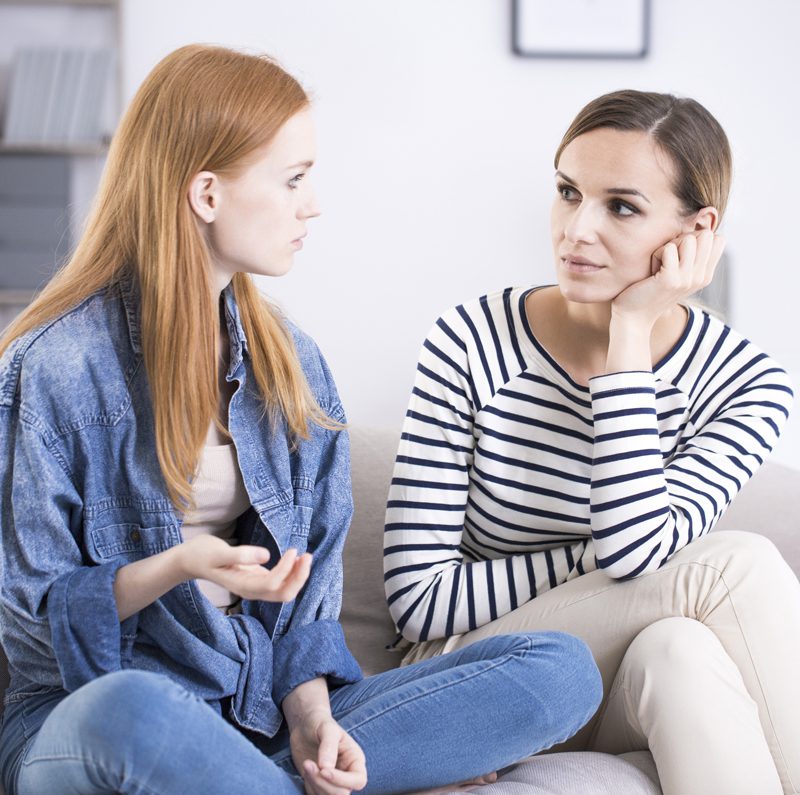 two women talking together on the couch
