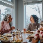 A family gathered around a dining table, sharing a meal and laughing together near large windows on a winter day.